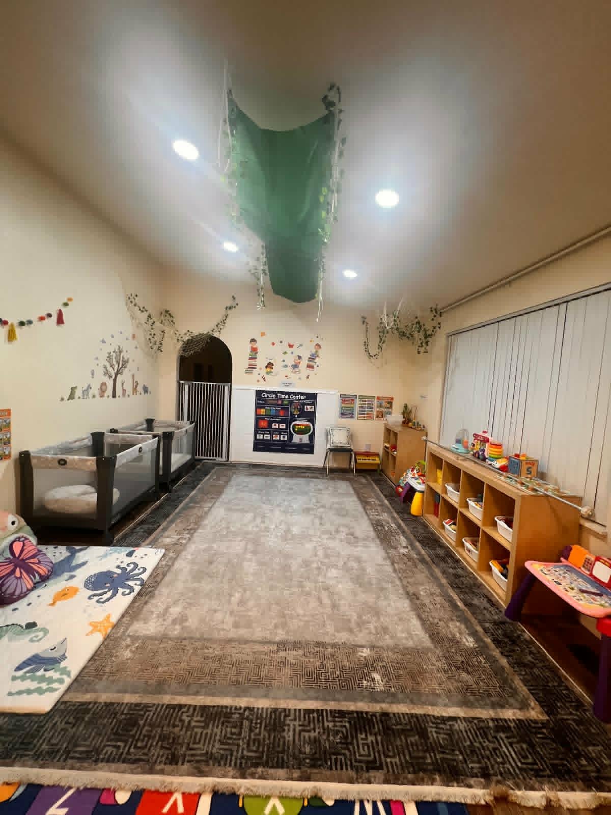 Infant and toddler room with cribs and soft play area